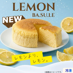 爽やかな水色背景に、白い皿に乗せた「LEMON BA.SU.LE」チーズケーキを配置した商品ビジュアル。ふんわり焼き上げたレモンチーズケーキを1カット取り分け、中のしっとりなめらかな断面を見せている。周囲にはカットレモンを散りばめ、初夏らしい爽やかさを演出。上部には「LEMON BA.SU.LE」「NEW」の文字、下部には「レモンより、レモン。」のキャッチコピーをデザインした広告画像。